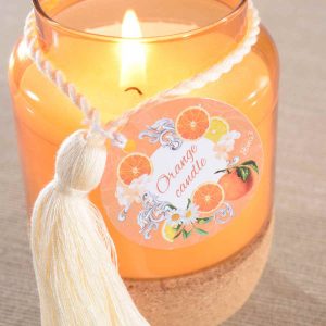Bougie parfumée Celes’Tea senteur Orange – pot de verre orange avec base liège et pompon – ambiance lumineuse et chaleureuse du salon de thé du Neubourg.